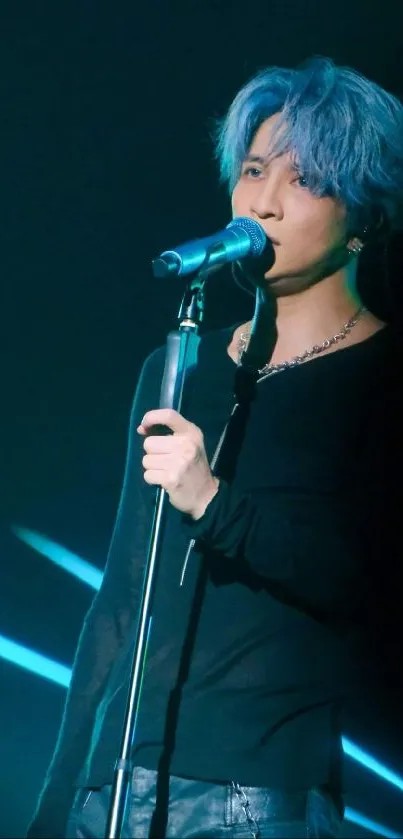 Singer with blue hair performing on stage, illuminated by lights.