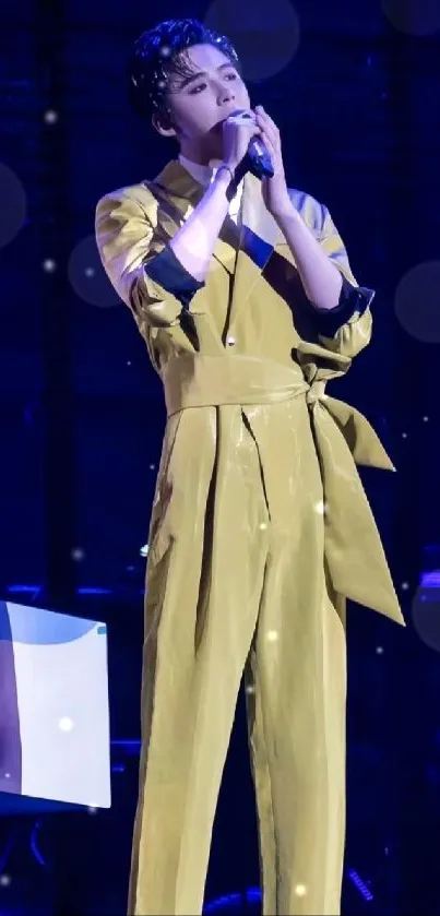 Singer in yellow outfit performing on stage with vibrant background.