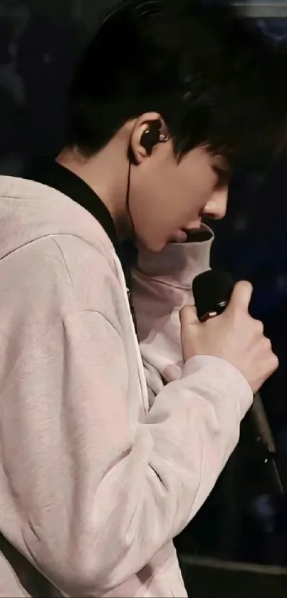 Singer in white hoodie holding a microphone during a performance.