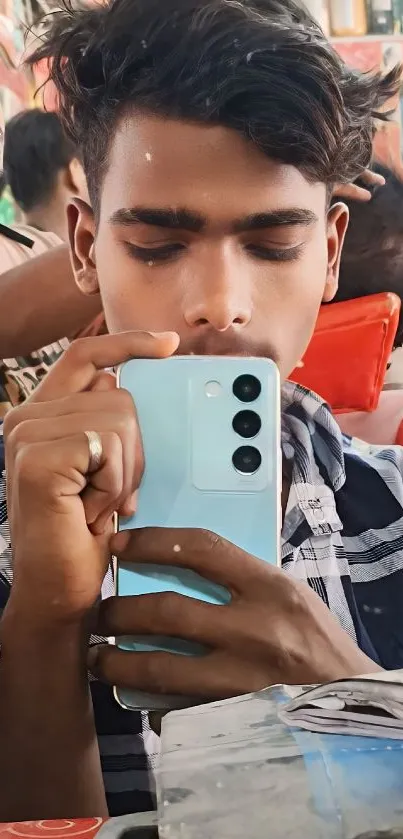 A stylish man taking a mirror selfie with a sleek smartphone.