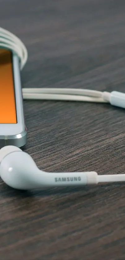 Smartphone with earphones on a wooden surface.