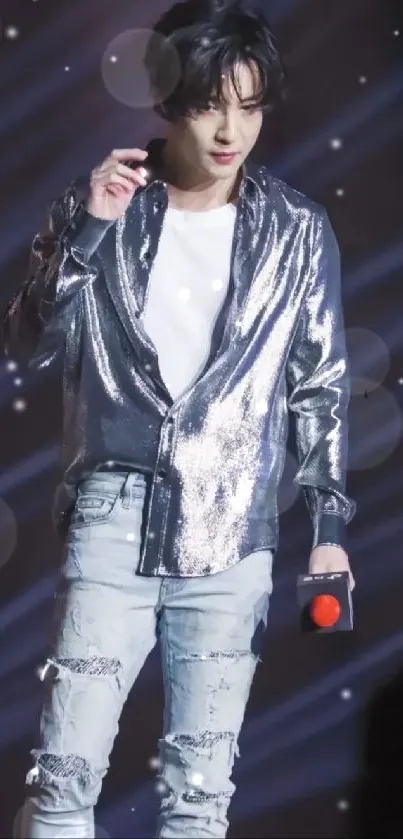 Performer in shimmering outfit with distressed jeans on stage.