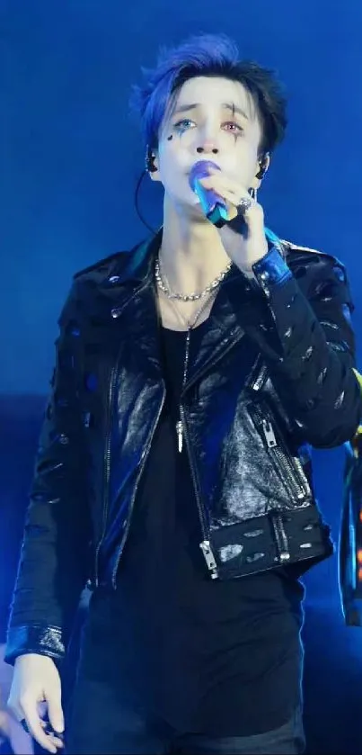 Performer on stage with blue lights and leather jacket.