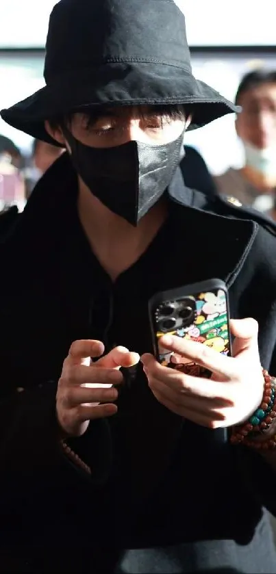 Person in black outfit, holding a patterned phone