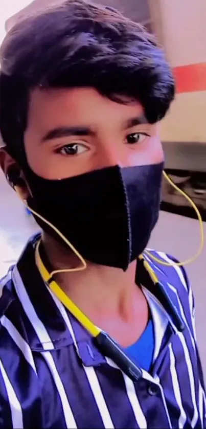 Stylish young person in a black mask and striped shirt at a train station.