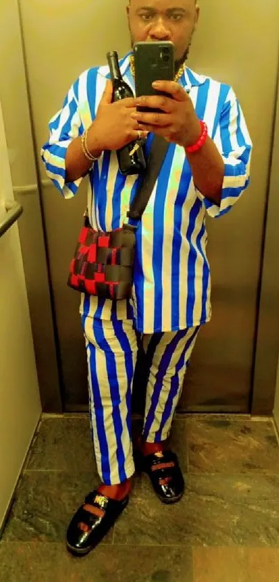 A person in a stylish blue and white striped outfit takes a selfie.