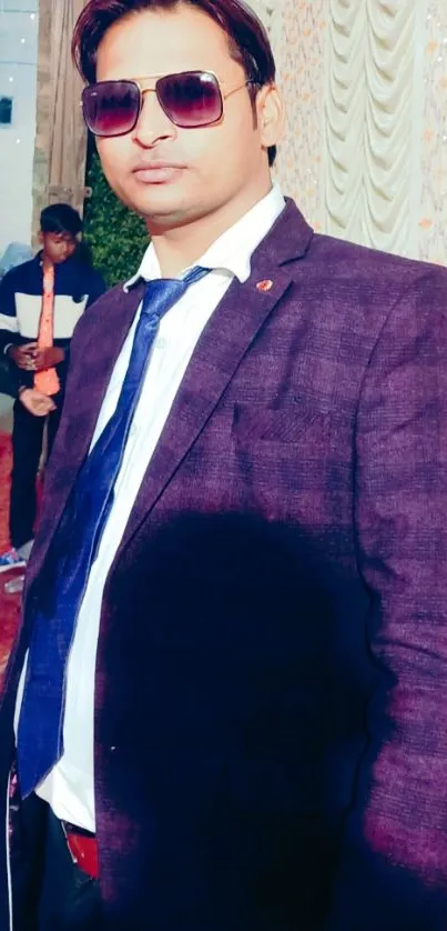 Person in a stylish dark purple suit with sunglasses.