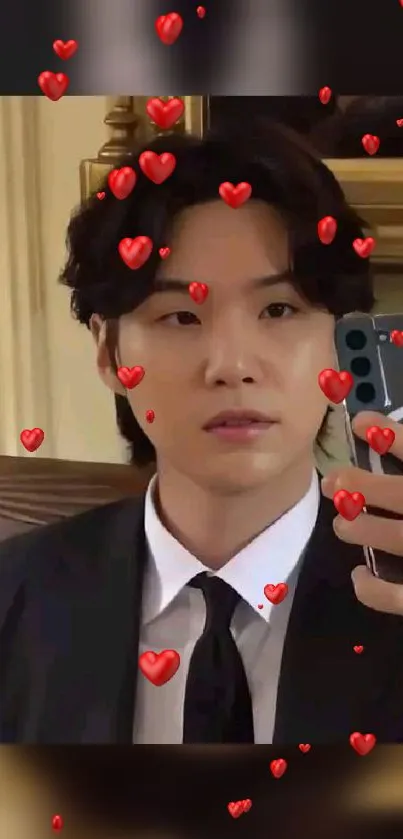 Person in suit taking a selfie with floating red hearts on mobile wallpaper.