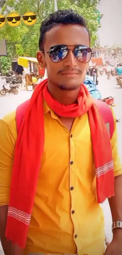 Fashionable guy with sunglasses, yellow shirt, and red scarf on a street.