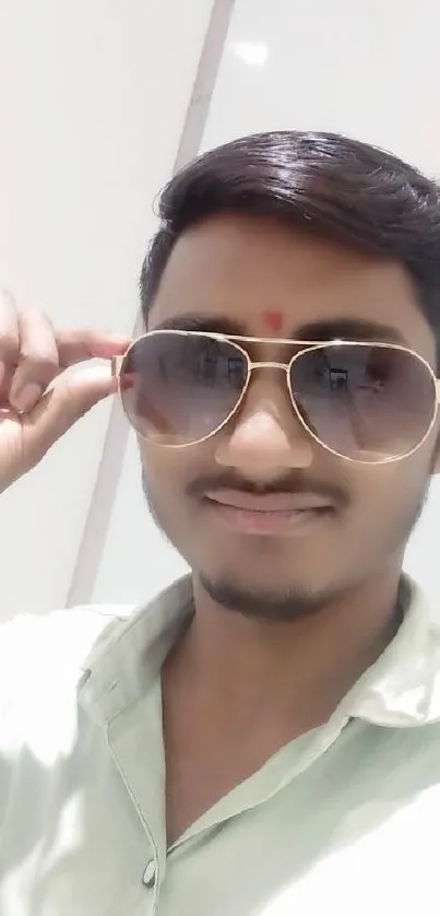 A stylish man wearing sunglasses with a beige background.