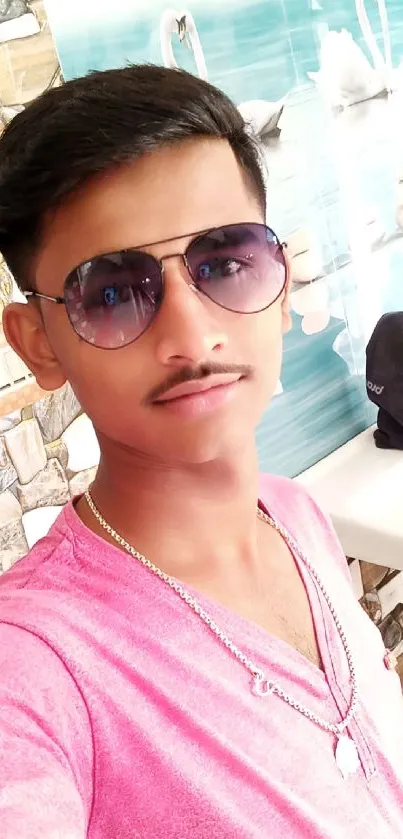 Selfie of a young man in sunglasses and a pink shirt in a stylish setting.