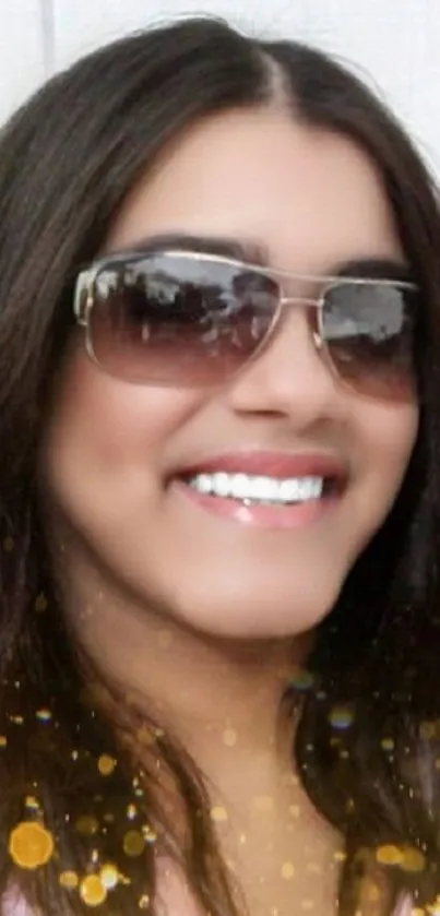 Smiling woman with sunglasses and sparkles on wallpaper.