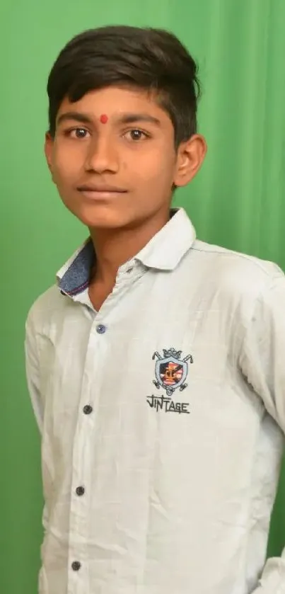 Portrait of a teenage boy standing in front of a green backdrop.