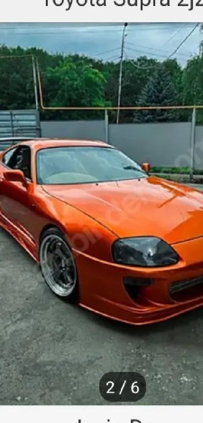 Vibrant orange Toyota Supra sports car on a phone wallpaper background.