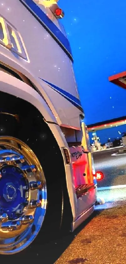 Modern truck parked at a brightly lit gas station at night.