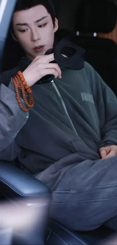 Person in gray outfit sitting in a car with a relaxed pose.