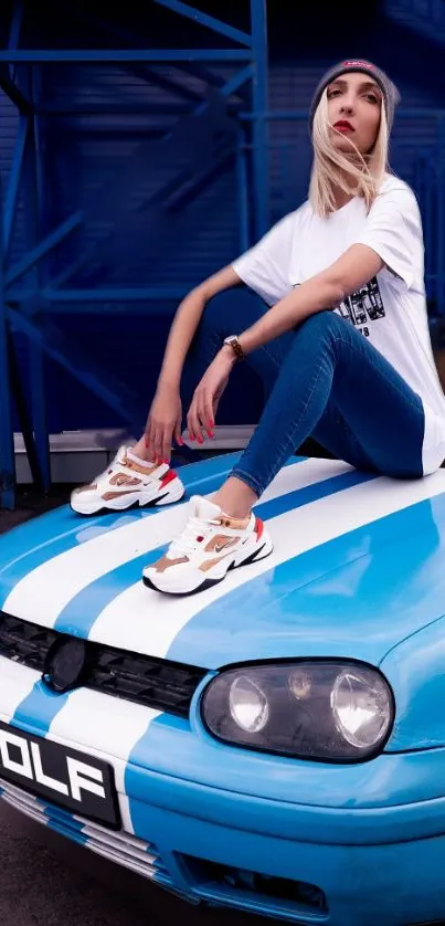 Person sitting on a blue sports car in urban setting.