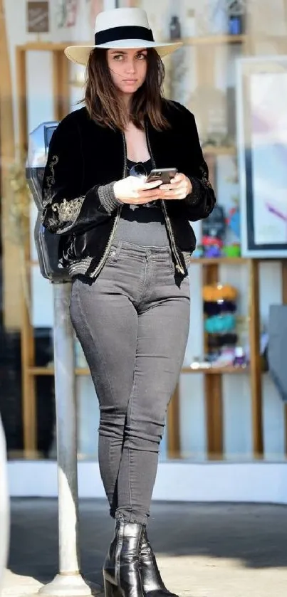 Stylish woman in black outfit with hat and boots walking outdoors.