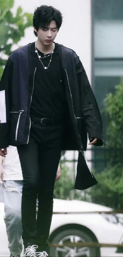 Man in stylish black outfit walking in an urban setting, exuding modern fashion.