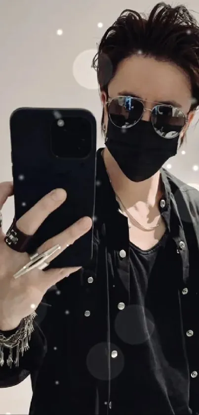 Fashionable person with sunglasses and black outfit taking a selfie.