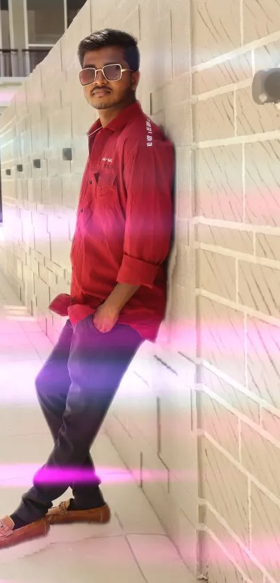 Stylish man in red shirt against beige wall with pink and blue hues.