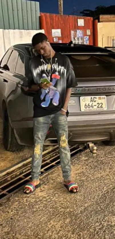 A fashionable person stands by a luxury car at night, showcasing urban style.