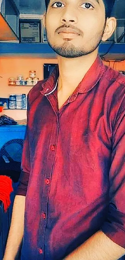 Young man in a red shirt standing in a small retail shop interior.