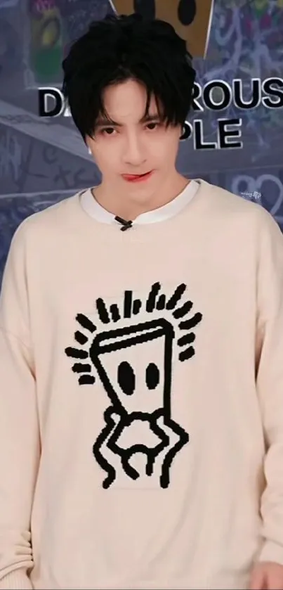 Person wearing a beige sweatshirt with graffiti design.