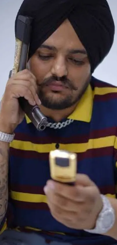 Man in striped shirt with phone and gun accessory.