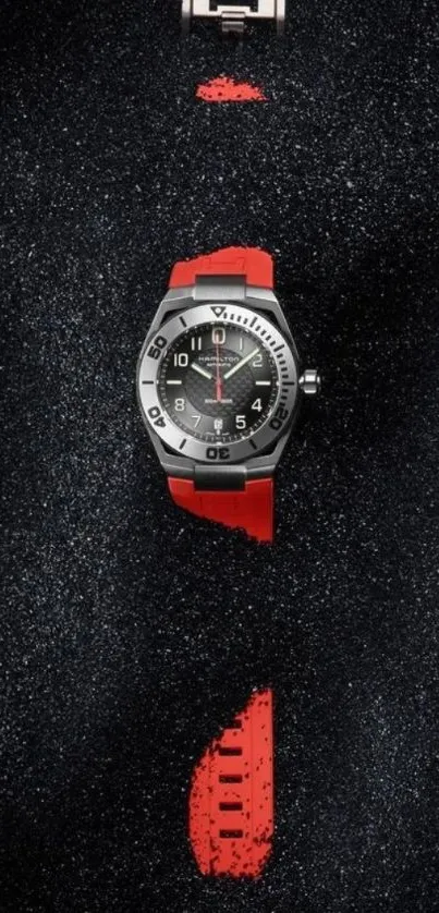 Watch with red strap on textured black background.