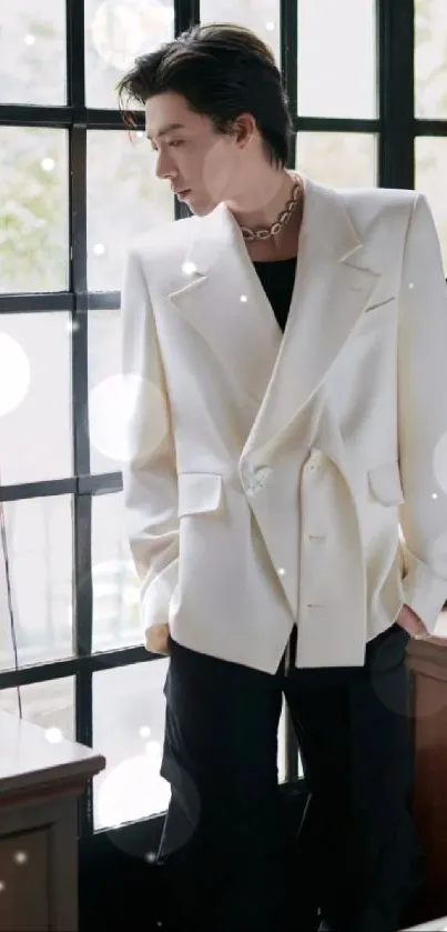 Person in white jacket standing by window, stylish portrait.