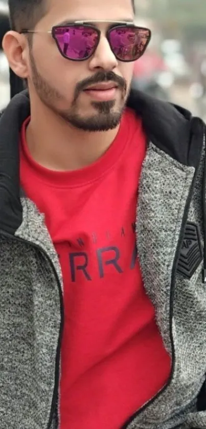 Man in red shirt and grey jacket with sunglasses.