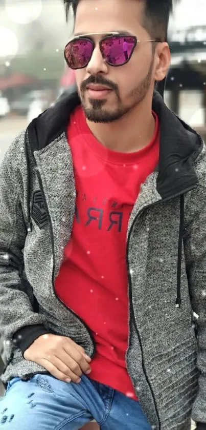 Man in gray jacket and red shirt posing stylishly outdoors.