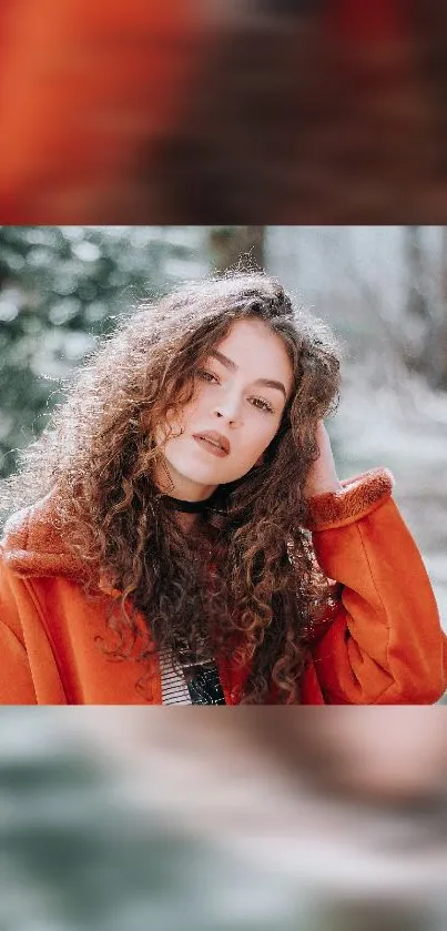 Woman in orange coat with curly hair in a winter setting.