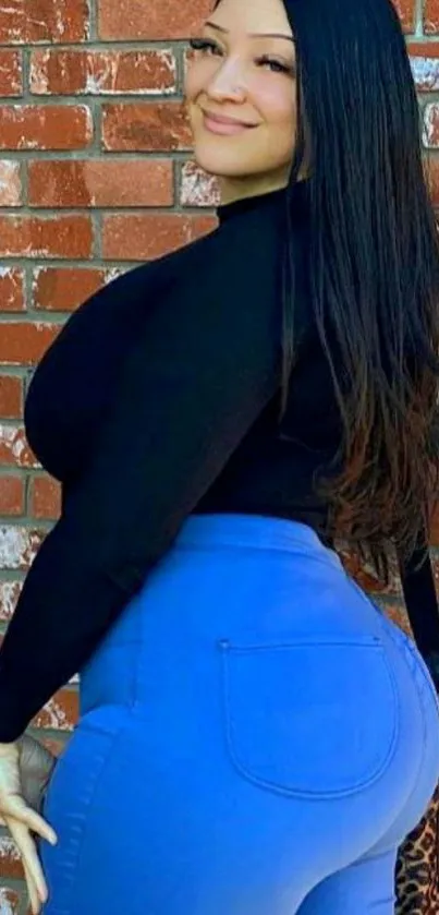 Woman in blue jeans against a textured brick wall.