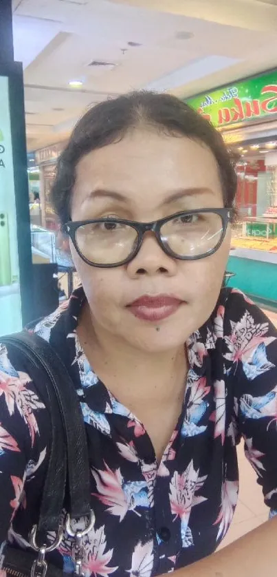 Woman in floral shirt, mall setting.