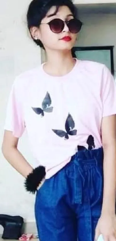 Person wearing a pink shirt with a butterfly design and blue jeans.