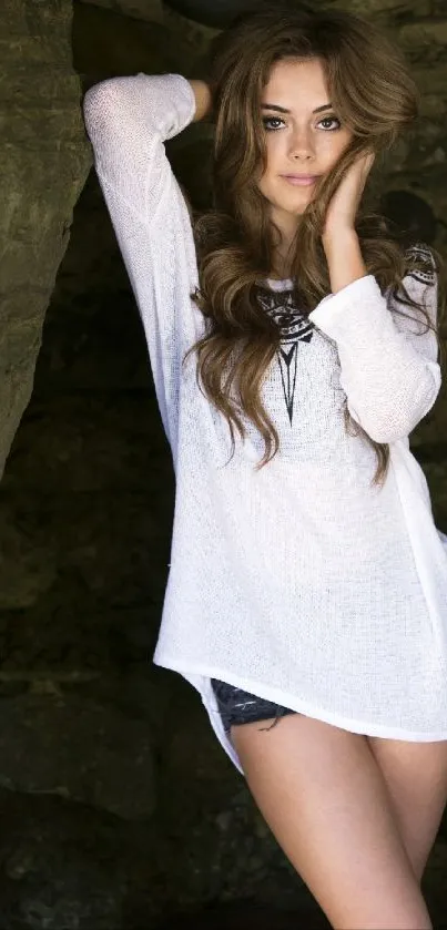 Woman in white top poses in natural rocky setting.