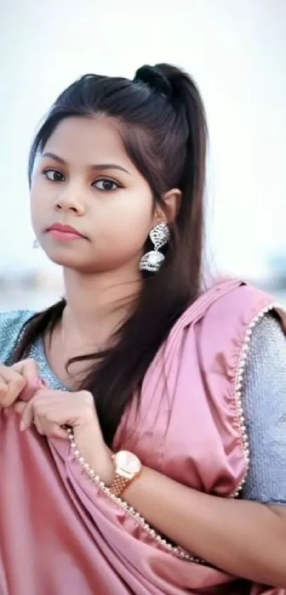 Woman in pink sari with serene expression.