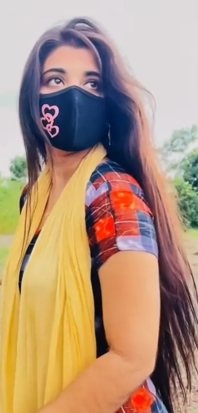 Woman with long hair, wearing a mask and plaid shirt in nature.