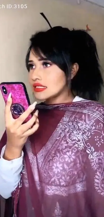 Woman in magenta shawl using a smartphone.