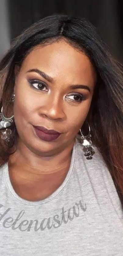 Portrait of a stylish woman with makeup and accessories in a gray top.