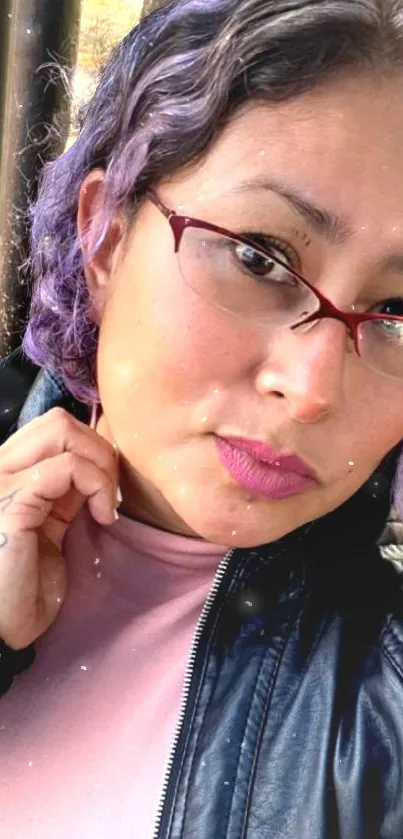 Stylish woman with purple hair and glasses in a casual jacket.