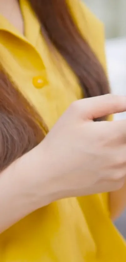Person in yellow shirt holding a phone.