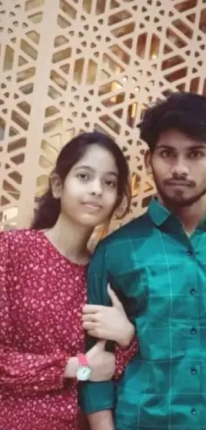 Young couple posing against a beige geometric background.