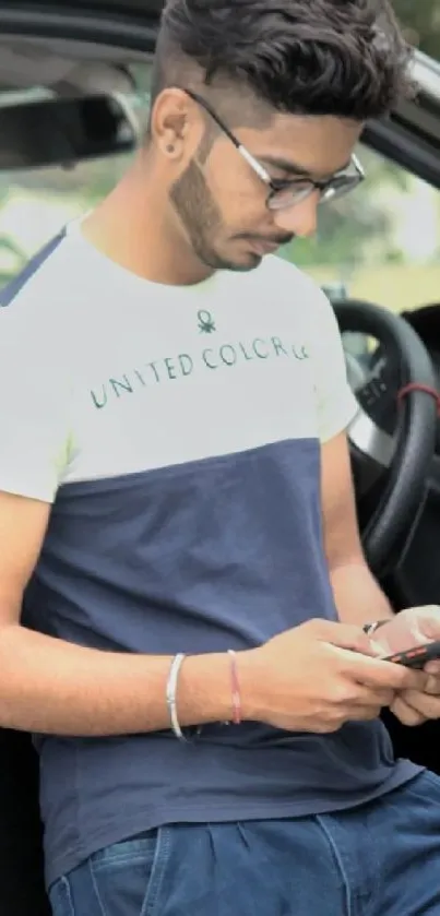 Young man leaning on car, using smartphone.