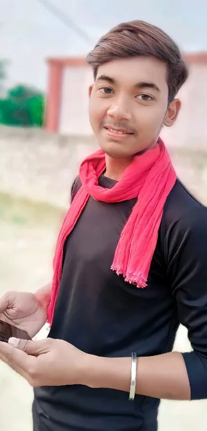 A young man with a red scarf holds a phone, exuding style.