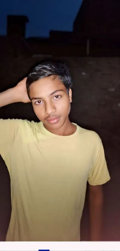 Portrait of a young person in a casual pose at night with a brown background.