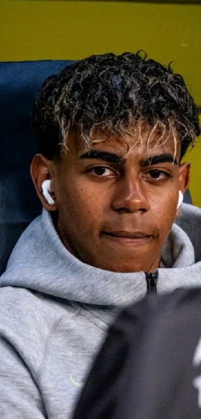 Young man with headphones in gray hoodie.