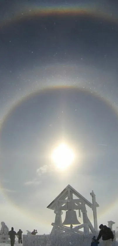 Sun halo over snowy landscape with people and structure.